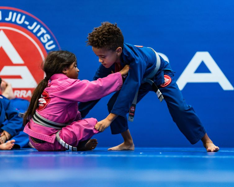 Children practising Brazilian Jiu‑Jitsu grips on the mats